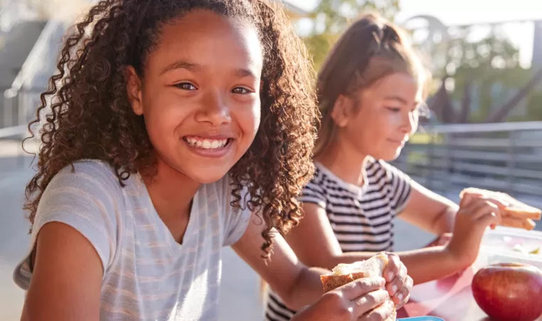 two happy girls enjoying lunch outside