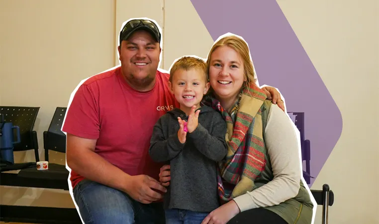 2 parents and a child smiling at the camera