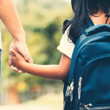 mother and child holding hands walking to school