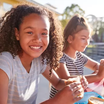 two happy girls enjoying lunch outside