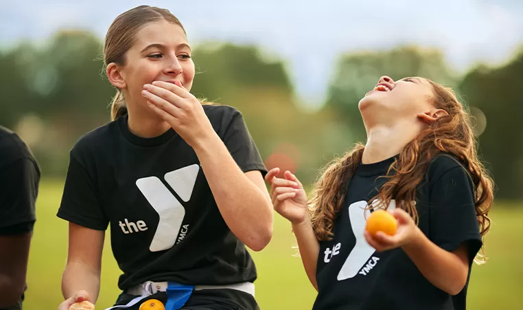 2 girls eating oranges and laughing
