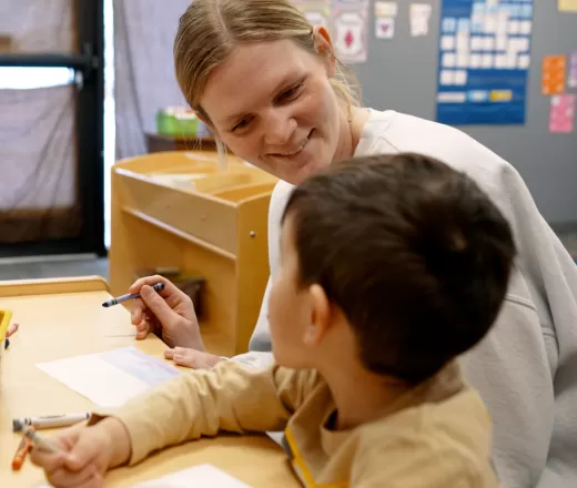 child and teacher coloring together